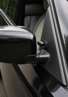 Musta hirvipilli kiinnitettynä auton sivupeilin viereen.